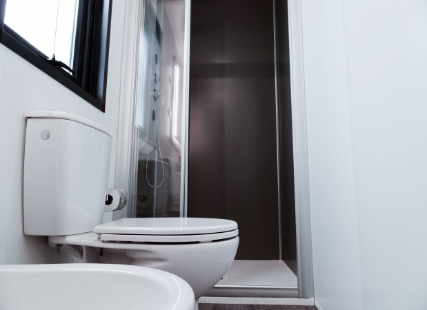 Bagno moderno con doccia, WC e lavabo di colore bianco.