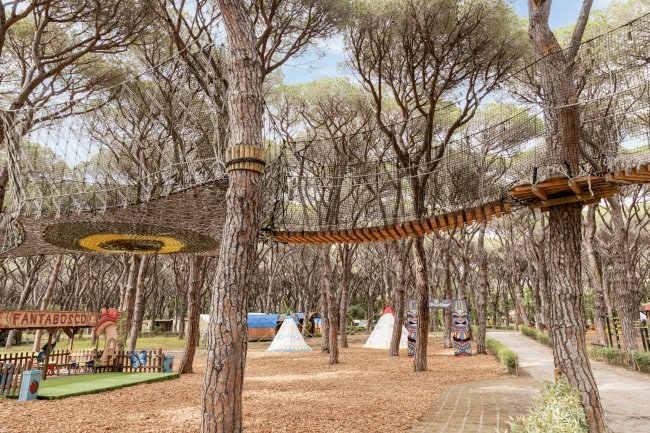 Percorso avventura sopraelevato tra gli alberi in un parco con strutture colorate.