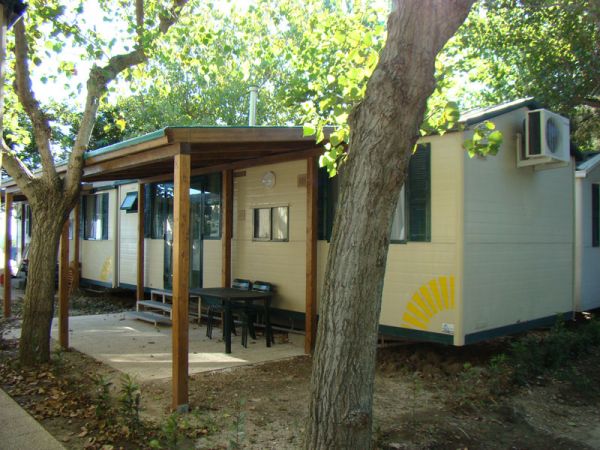 Casa mobile con veranda in legno tra gli alberi.