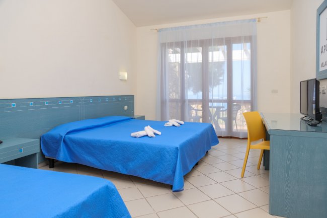 Camera d'hotel con letto matrimoniale e lenzuola blu.