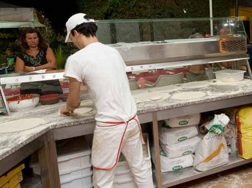 Un pizzaiolo prepara impasti su un bancone.