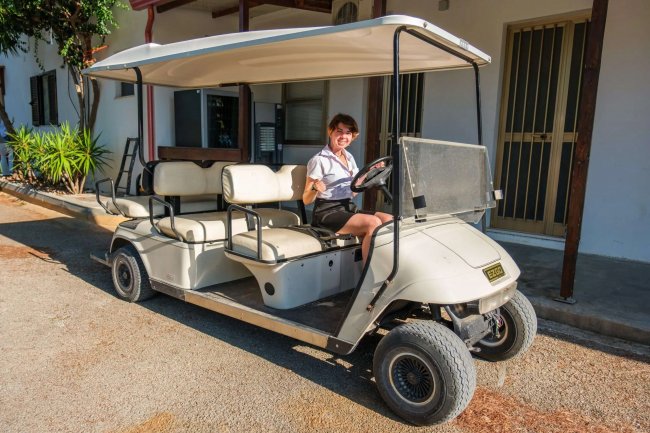 Persona seduta su una golf car bianca parcheggiata.