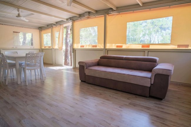 Sala con divano, tavolo e finestre luminose.