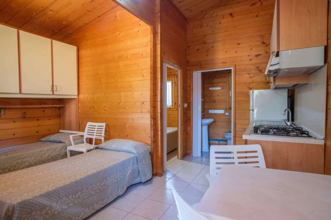 Camera in legno con due letti singoli, cucina e bagno.