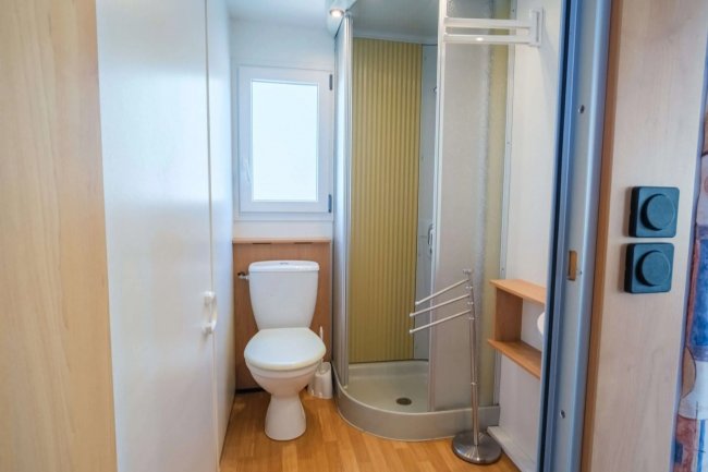 Bagno con doccia angolare, parquet chiaro e sanitari bianchi. Finestra luminosa.