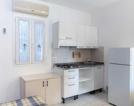 Cucinino bianco con finestra e frigorifero.