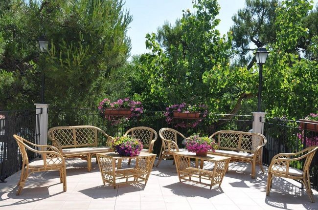 Un patio con mobili in vimini e fiori colorati.