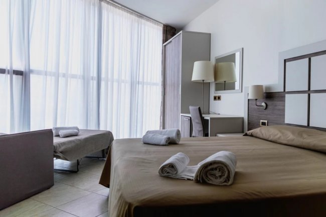 Camera da letto con letto matrimoniale, tende lunghe e scrivania.