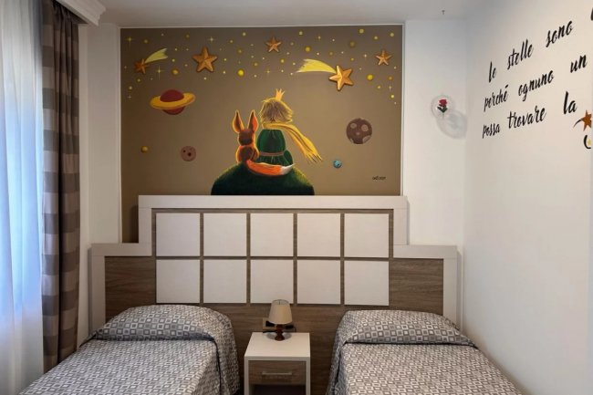Due letti singoli con un murale del Piccolo Principe e una volpe.