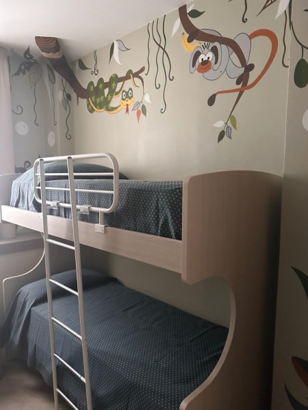 Camera con letto a castello, decorata con disegni di animali e piante.