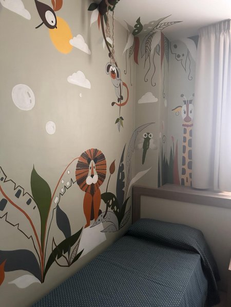 Camera con letto singolo, decorata con immagini di animali e piante stilizzate.
