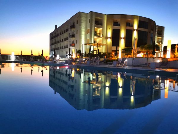 Luminoso edificio illuminato riflesso in una piscina al tramonto.