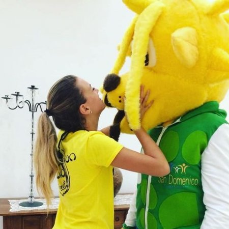 Persona abbraccia e bacia un costume da mascotte giallo.