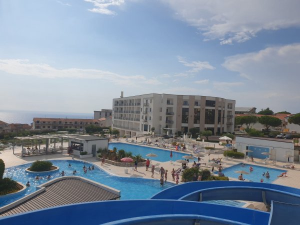 Vista di un complesso con piscine all'aperto e persone che nuotano.