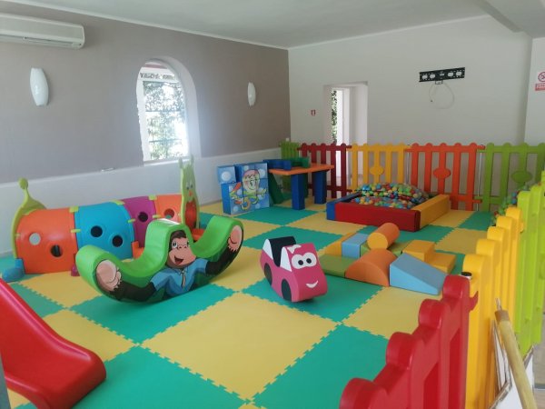 Area giochi colorata per bambini con scivoli e giochi morbidi.