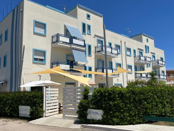 Edificio bianco con dettagli blu e tende da sole gialle.