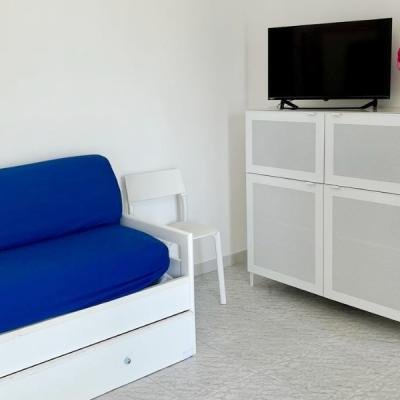 Salotto con divano blu, sedia bianca e mobile TV bianco.