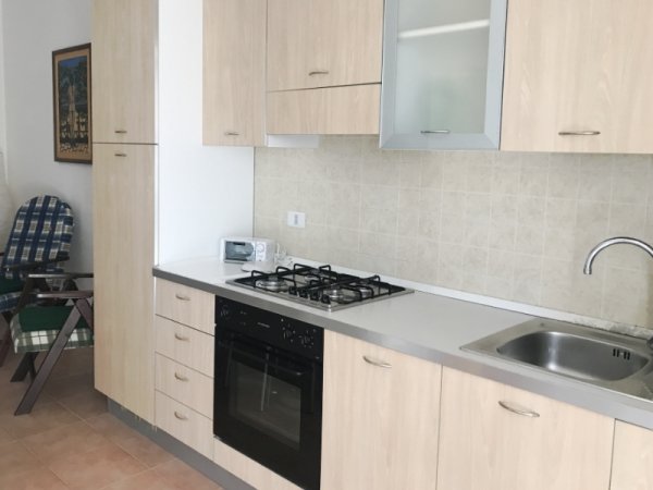 Cucina moderna con mobili in legno chiaro, piano cottura a gas e lavello.