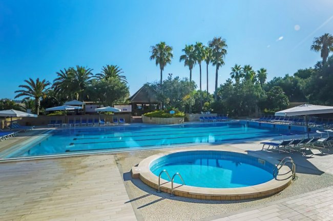 Piscina all'aperto circondata da palme.