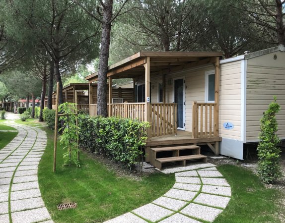 Una casa mobile con veranda in un campeggio alberato.