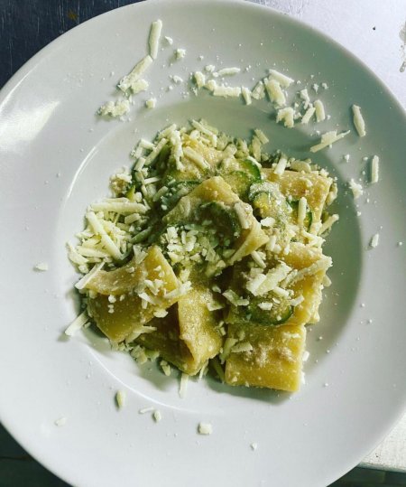 Un piatto di pasta con zucchine e formaggio grattugiato.