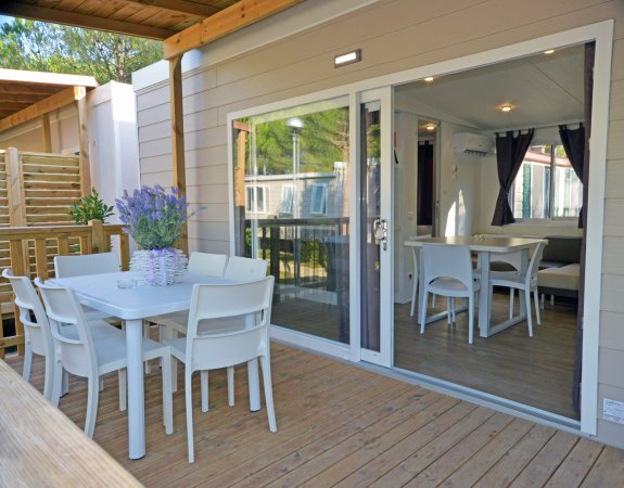 Veranda con tavolo bianco e sedie, vicino a una porta scorrevole di vetro.