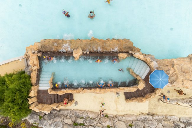 Vista dall'alto di una piscina con cascate e persone.