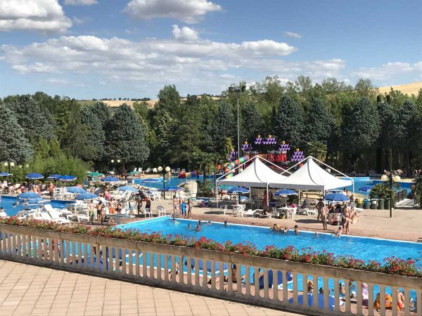 Panoramica di piscine affollate con tende e scivoli.