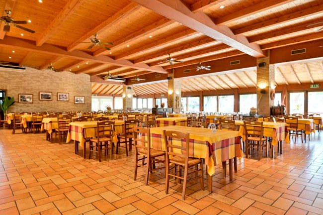 Ristorante ampio con tavoli apparecchiati in giallo.