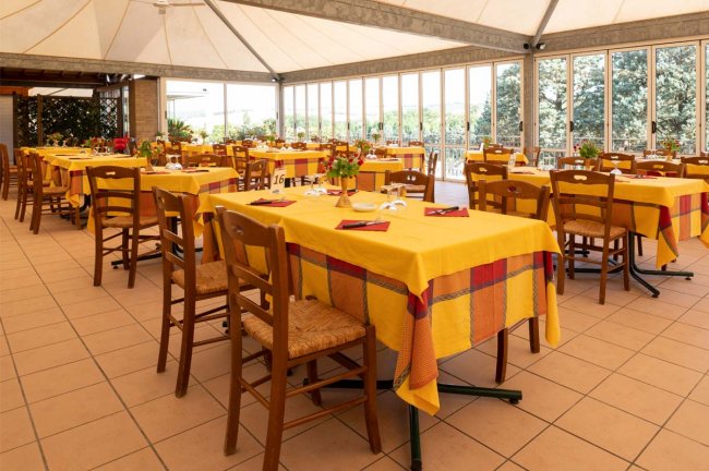 Sala ristorante con tavoli gialli apparecchiati.