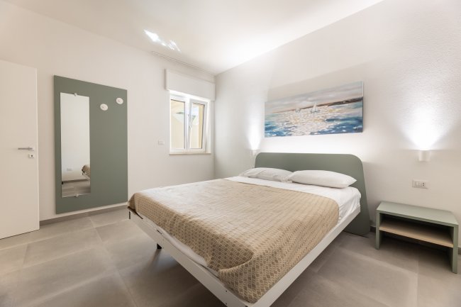 Camera da letto con quadro, letto matrimoniale e finestra.