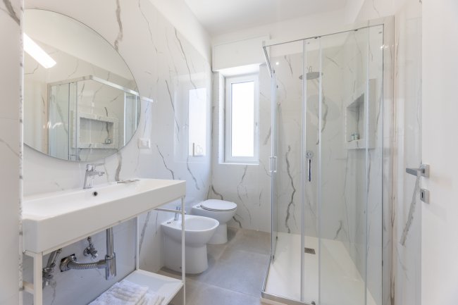 Bagno luminoso con doccia e finestra.