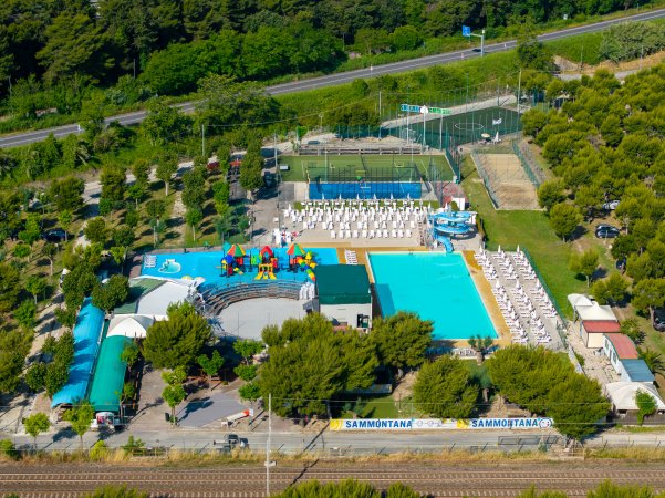 Parco acquatico con piscina e giochi, circondato dal verde.