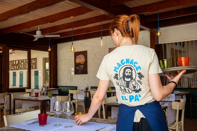 Cameriera in ristorante con bicchieri e tavoli apparecchiati.