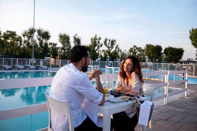 Coppia cena all'aperto vicino a una piscina.