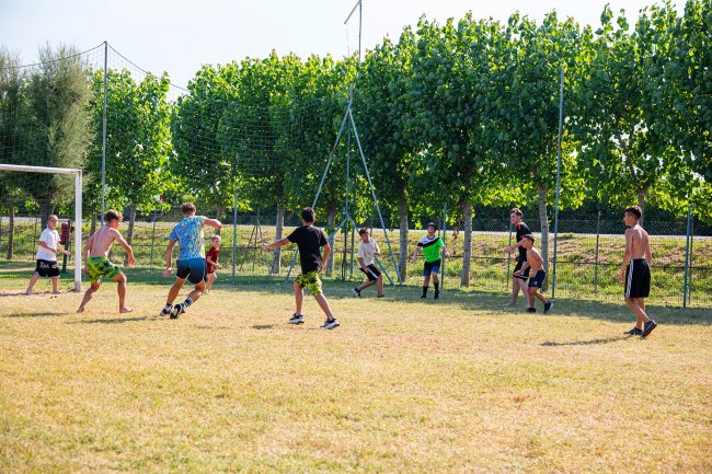 Ragazzi giocano a calcio su campo erboso.