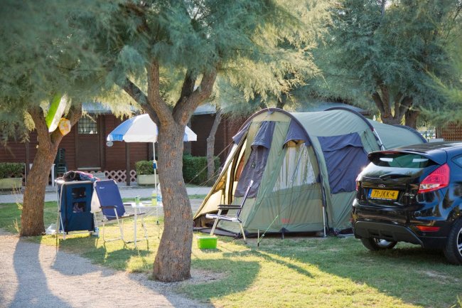 Tenda con tavoli e sedie vicino a un'auto in campeggio.