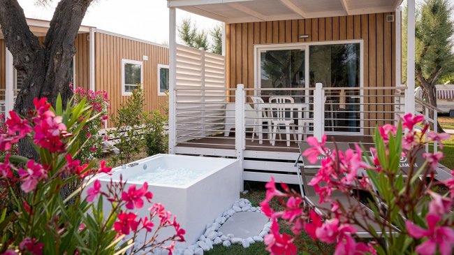 Casa vacanze con terrazza, vasca e fiori rosa.
