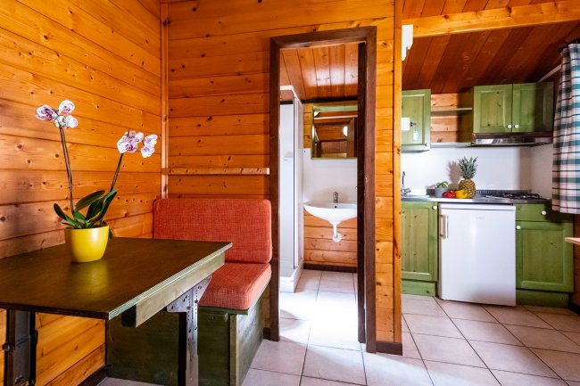 Interno di legno, tavolo verde, cucina verde e bianca.