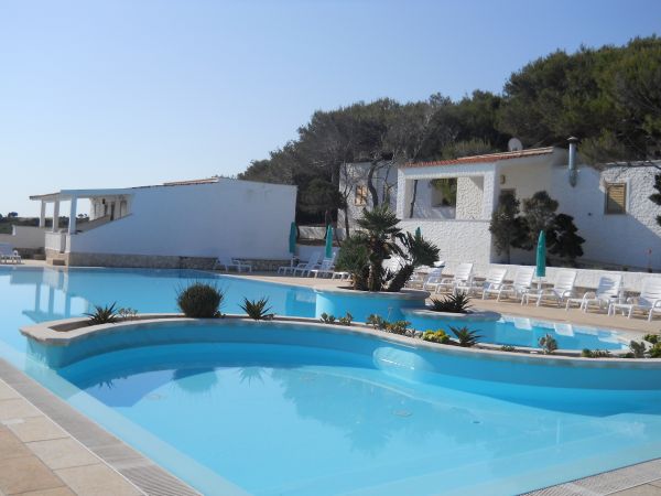 Piscina azzurra circondata da lettini e ombrelloni.