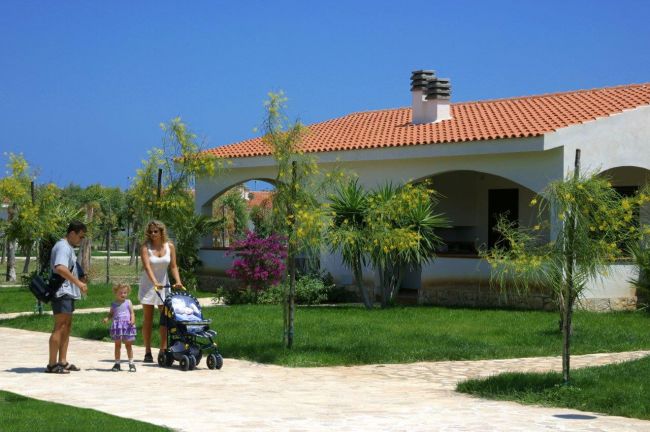 Famiglia passeggia su un vialetto accanto a una casa con tetto arancione.