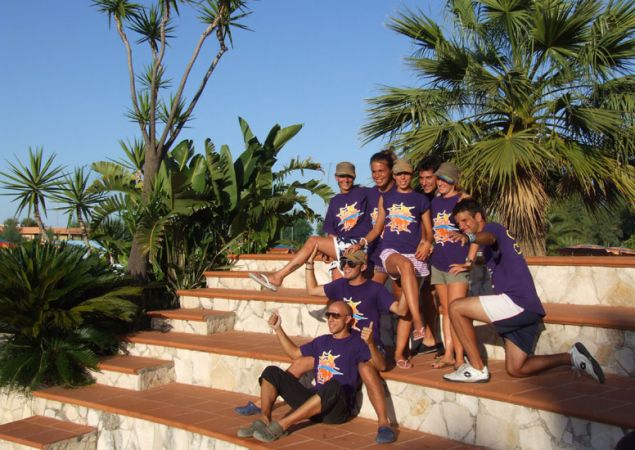 Gruppo di persone in magliette viola su gradini circondati da palme.