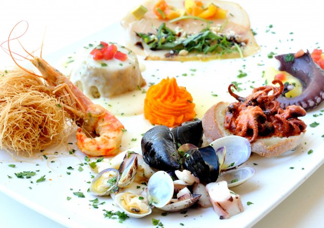 Un piatto di frutti di mare assortiti con erbe e verdure.