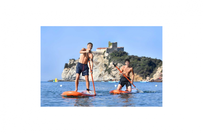 Due persone fanno paddleboarding vicino a una costa con un castello.