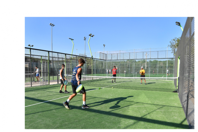 Persone giocano a padel in un campo recintato, cielo terso.