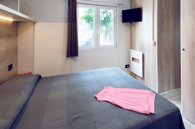 Stanza con letto grigio, finestra e TV.