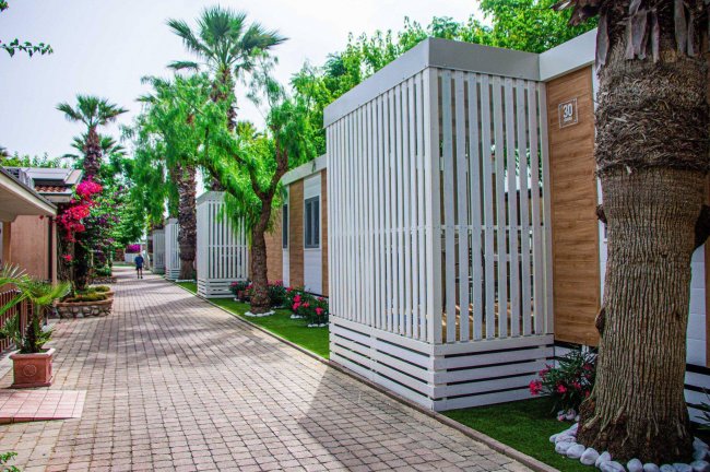 Un viale esterno con bungalow dai colori chiari e palme lungo il percorso.