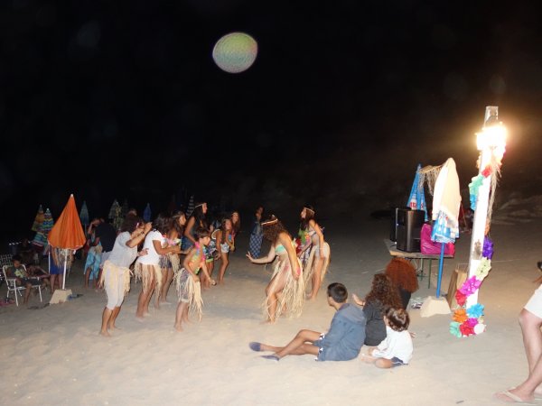 Festa sulla spiaggia di notte con persone che ballano.