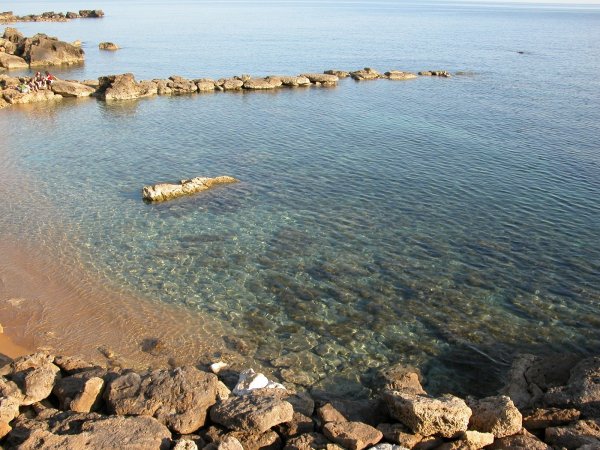 Una piccola baia con acqua cristallina e rocce lungo la riva.