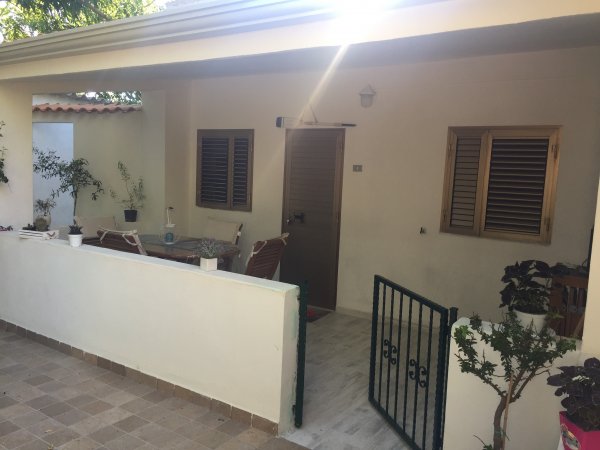 Un patio con tavolo da esterno, circondato da piante e un cancello.